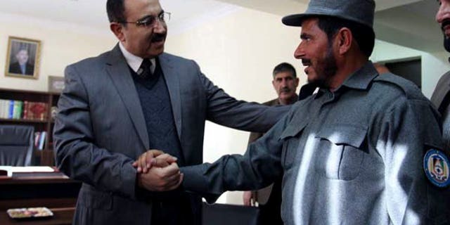 Afghanistan's Interior Minister Mujtaba Patang (left) speaks with a police officer in Kabul, on December 25, 2012. Afghanistan's parliament has sacked Patang -- one of the country's most powerful security chiefs -- less than a year after he took office.