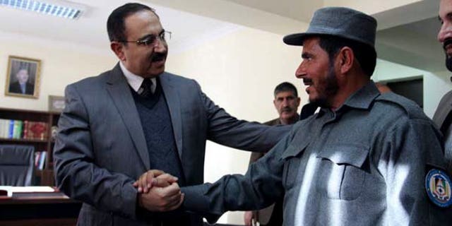 Afghanistan's Interior Minister Mujtaba Patang (left) speaks with a police officer in Kabul, on December 25, 2012. Afghanistan's parliament has sacked Patang -- one of the country's most powerful security chiefs -- less than a year after he took office.