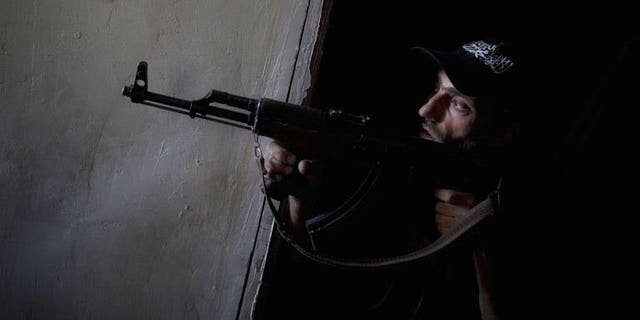 A Syrian rebel fighter points his gun towards pro-regime forces during clashes in the Salaheddine district of Aleppo, on July 9, 2013. Syria's rebels have seized the strategic town of Khan al-Assal, a regime bastion situated in the northern province of Aleppo, according to the Syrian Observatory for Human Rights.