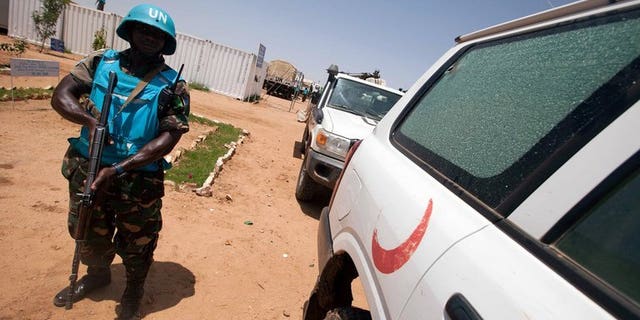 A UNAMID military peacekeeper from Tanzania stands next to a damaged ambulance on July 14, 2013 in South Darfur. Tanzania's president called for the beefing up of the protection capacity of peacekeepers in the hybrid UN/African Union force in Sudan's Darfur region, after seven peacekeepers were killed there in an ambush.