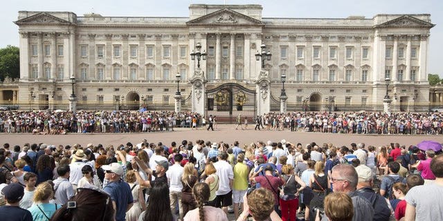 Crowds of tourists gather on the steps of the Queen Victoria Memorial Statue outside Buckingham Palace in central London on July 22, 2013.