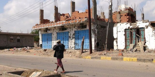 A Yemeni man walks past destroyed buildings in Zinjibar, capital of Abyan province in southern Yemen on December 5, 2012. Yemeni authorities have released a journalist who had been detained for three years on charges of promoting Al-Qaeda, the state news agency Saba reports.