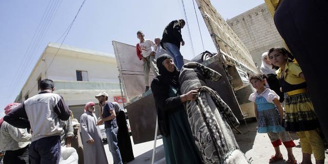 A Syrian woman carries her belongings upon her arrival in the Bekaa valley where she will find shelter, on June 14, 2013. The Lebanese government has imposed new entry controls on Syrians in a bid to reduce friction between the host population and the 600,000 who have already crossed.
