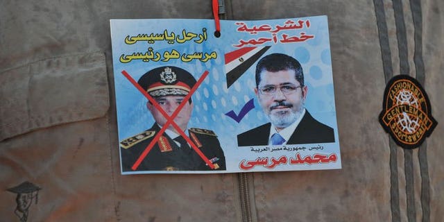 A sticker on the shirt of a supporter of Egypt's ousted president Mohamed Morsi shows Morsi (R) with text above it reading in Arabic: "Legitimacy is the red line" and one of army chief Abdel Fattah al-Sisi (L) with text above reading in Arabic: "Leave Sisi, Morsi is the president" outside Cairo's Rabaa al-Adawiya mosque on July 24, 2013.