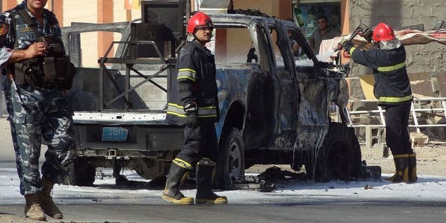 Iraqi firefighters extinguish fire from a vehicle at the site of an explosion near the northern city of Kirkuk on July 25, 2013. Bombs exploded near shops and cafes in Iraq on Thursday night, killing at least 17 people, officials said.