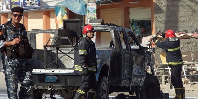 Iraqi firefighters extinguish fire from a vehicle at the site of an explosion near the northern city of Kirkuk on July 25, 2013. Bombs exploded near shops and cafes in Iraq on Thursday night, killing at least 17 people, officials said.