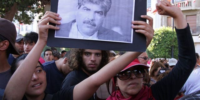 Tunisians hold a portrait of slain opposition politician Mohamed Brahmi on July 25, 2013. Tunisian Interior Minister Lotfi Ben Jeddou has said that Brahmi was killed with the same weapon as fellow opposition figure Chokri Belaid.