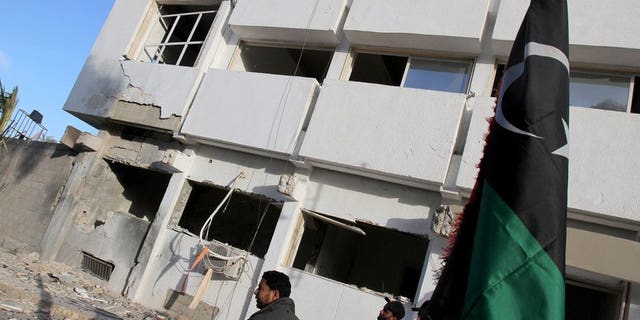 Libyan security forces and bystanders walk outside a damaged police station on April 27, 2013 in Benghazi. A marksman shot dead a prominent Libyan political activist as he emerged from Friday prayers at a mosque in the restive eastern city of Benghazi, a security official said.