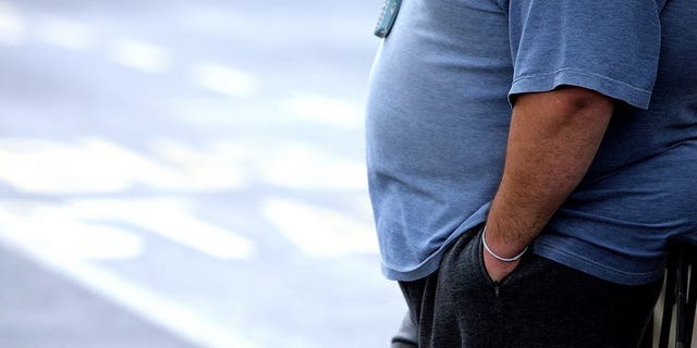 This file illustration photo shows an overweight man standing at a bus stop. An obese South African man has been told he is too fat to live in New Zealand despite shedding 30 kilograms since he moved to the country six years ago.