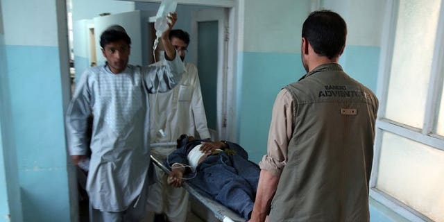 Medical staff carry a wounded man at the main hospital in Ghazni after a suicide attack in Qara Bagh district, on July 26, 2013. A suicide bomber riding a motorcycle struck a busy marketplace and killed seven people, including an anti-Taliban militia leader.