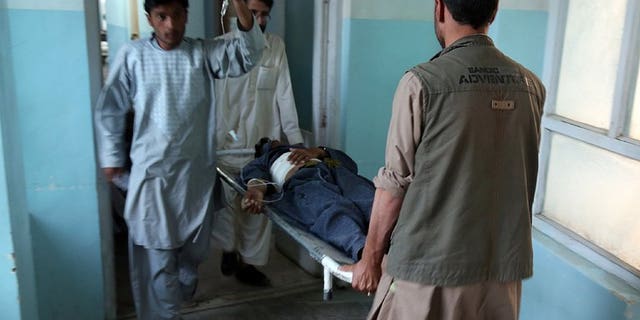 Medical staff carry a wounded man at the main hospital in Ghazni after a suicide attack in Qara Bagh district, on July 26, 2013. A suicide bomber riding a motorcycle struck a busy marketplace and killed seven people, including an anti-Taliban militia leader.