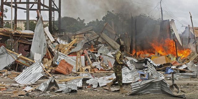 A Somali National Government (SNG) soldier walks past burning debris after a suspected suicide bomber rammed a car laden with explosives into an armoured convoy of African Union troops in Mogadishu on July 12, 2013. A suicide car bomb attack struck a Turkish embassy building in Mogadishu Saturday, killing one Somali civilian and wounding two Turkish policemen, a diplomat and a witness said.