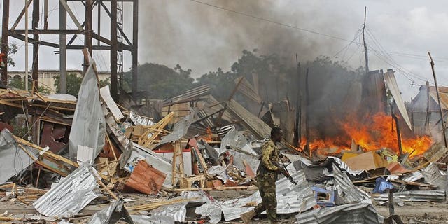 A Somali National Government (SNG) soldier walks past burning debris after a suspected suicide bomber rammed a car laden with explosives into an armoured convoy of African Union troops in Mogadishu on July 12, 2013. A suicide car bomb attack struck a Turkish embassy building in Mogadishu Saturday, killing one Somali civilian and wounding two Turkish policemen, a diplomat and a witness said.