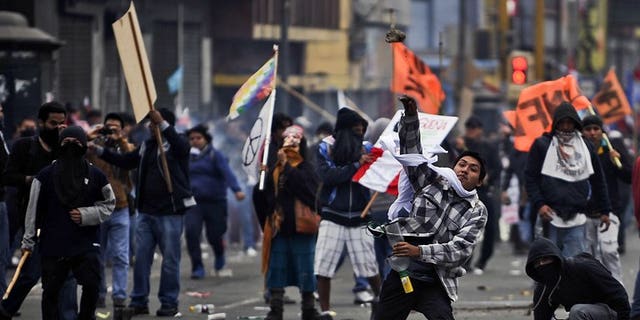 Demonstrators throw stones at riot police in Lima on July 27, 2013. Peruvian police used tear gas and water cannon to drive back thousands of demonstrators protesting against what they said were President Ollanta Humala's failed promises on schools and jobs.