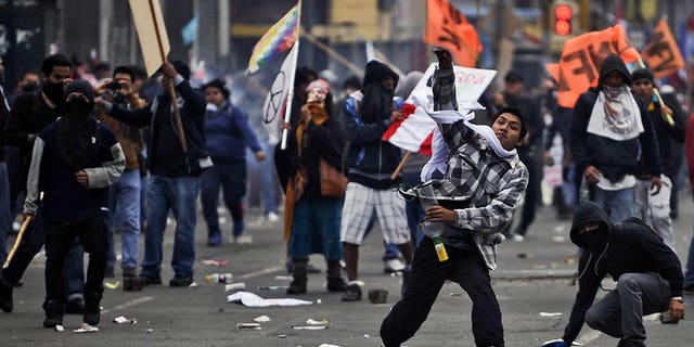 Demonstrators throw stones at riot police in Lima on July 27, 2013. Peruvian police used tear gas and water cannon to drive back thousands of demonstrators protesting against what they said were President Ollanta Humala's failed promises on schools and jobs.