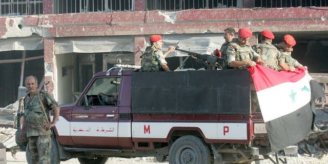 Syrian army troops patrol a ruined street in Qusayr in Homs province. The opposition Syrian National Coalition on Sunday condemned the reported "collective execution" by rebels of soldier prisoners in the north and said it had created a commission of inquiry.