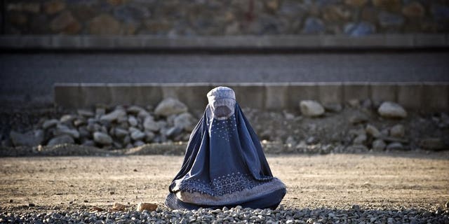A burqa-clad woman sits on the roadside in Kabul on August 19, 2009. The fate of Afghanistan's women hangs in the balance as the 2014 withdrawal of international forces looms, a UN human rights watchdog warned Monday, denouncing a raft of abuses there.