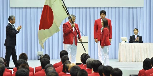 The head of the All Japan Judo Federation Haruki Uemura (C) holds the national flag at a ceremony in Tokyo in 2012. Uemura is to announce his resignation according to reports, after the sport was sullied in its birthplace by a series of scandals including abusive coaching, sexual harassment and misuse of funds.