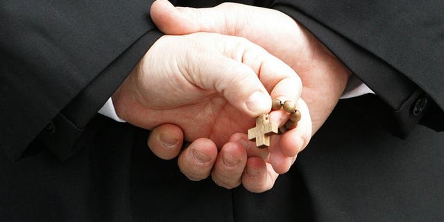 A priest in Rome holds a rosary on February 27, 2005. Scottish police are investigating claims of physical and sexual abuse at one of Scotland's best known Catholic boarding schools.