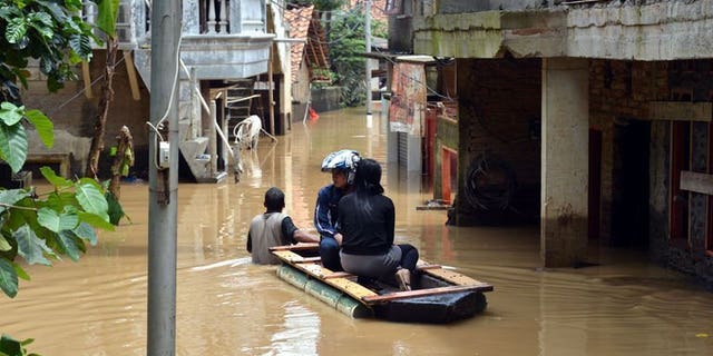 File picture shows residents in an improvised raft travelling down a flooded lane in south Jakarta on March 5, 2013 following heavy rains in nearby mountain areas. At least eight people are dead and five are missing after flooding and landslides hit eastern Indonesia, an official said on Tuesday.
