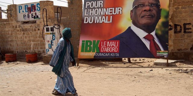 A man walks past an electoral placard of Ibrahim Boubacar Keita (dubbed IBK) reading "For Mali's Honor" on July 24, 2013 in a street of Timbuktu. Mali's former prime minister Keita has taken a wide lead in the presidential poll, initial results showed Tuesday.