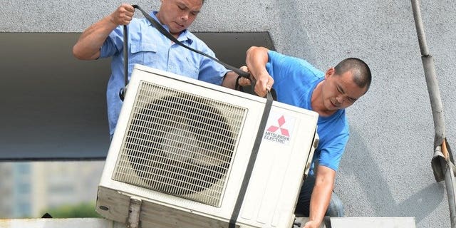 Workers install an air-conditioning unit at a food stall in Shanghai on July 2, 2013. More than 10 people have died in China's commercial hub Shanghai, a local health official said Wednesday as the city grapples with its highest temperatures in at least 140 years.