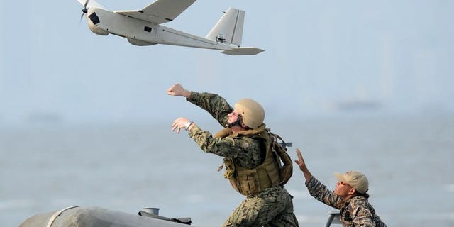 US and Philippine navy personnel launch an unmanned aerial vehicle (UAV) from a speed boat off the naval base in Sangley Point near Cavite City, on June 28, 2013. The Philippines has said US spy planes are providing crucial intelligence on Chinese military activities in disputed areas of the South China Sea.