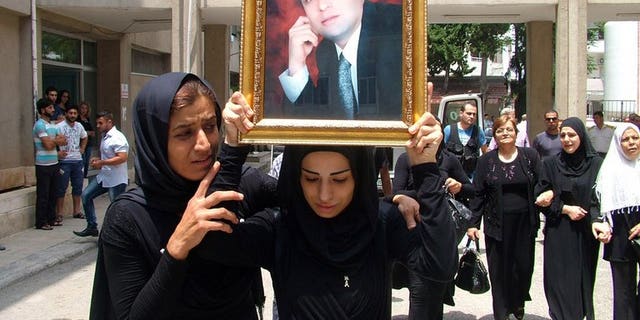 The daughter of Mohammad Darrar Jamo carries his portrait during his funeral in the Latakia province on July 19, 2013. The wife of the slain Syrian political analyst and ardent supporter of President Bashar al-Assad was charged in Lebanon on Wednesday with incitement to murder.