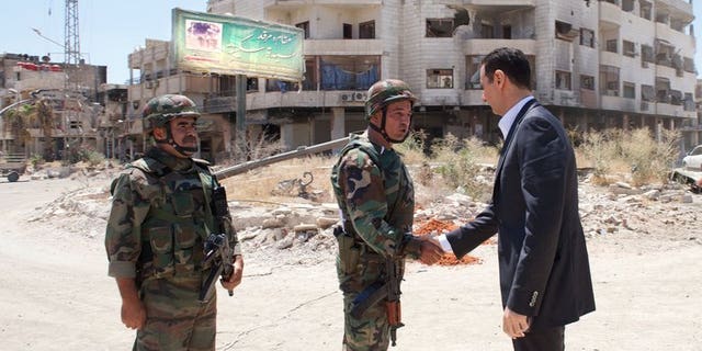 A handout picture released by the Syrian Arab News Agency (SANA) on August 1, 2013 allegedly shows Syrian President Bashar al-Assad shaking hands with a soldier in Daraya, southwestern of the capital Damascus.