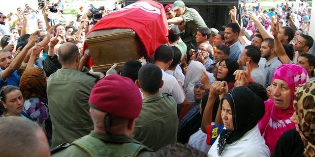 Tunisian soldiers carry the coffin, draped in the Tunisian flag, of one of the eight soldiers that was slain by militants in an ambush near the Algerian border, as they leave the hospital in Kasserine on July 30, 2013. Algeria's army has reinforced its forces along the eastern border with Tunisia, Interior Minister Daho Ould Kablia said on Thursday, days after the killing.