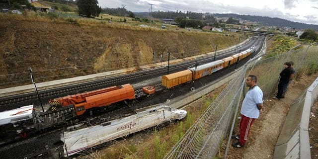 People look at part of a train that crashed in Angrois, near Santiago de Compostela, on July 27, 2013. The Spanish train was hurtling around a curve at 179 kph (111 mph), more than twice the speed limit, when it leapt off the tracks in a disaster that killed 79 people, a report on the contents of the "black box" recorders showed.