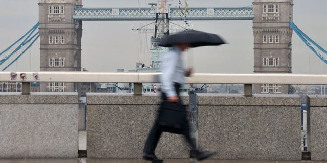A city worker walks over London Bridge in central London. London shares closed lower on Friday as markets tumbled on weak US nonfarm payroll employment figures, with sharp drops in William Hill and Smiths Industries accentuating the fall, dealers said.