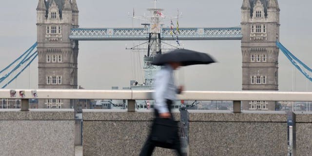 A city worker walks over London Bridge in central London. London shares closed lower on Friday as markets tumbled on weak US nonfarm payroll employment figures, with sharp drops in William Hill and Smiths Industries accentuating the fall, dealers said.