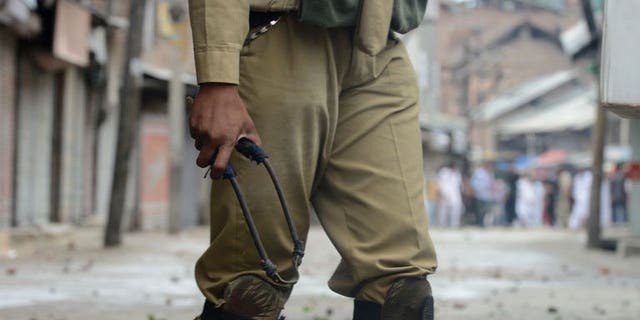 An Indian policeman holds a slingshot during clashes in downtown Srinagar on August 2, 2013. The Indian army said Friday it had killed 12 suspected militants in Kashmir in a forested area along the de facto border that divides the territory between India and Pakistan.