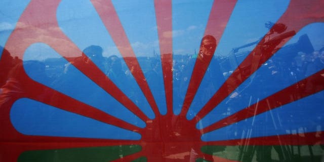 Demonstrators are photographed through a Romani flag as they march in Budapest on April 8, 2013. A verdict in the trial of four Hungarians accused of killing six Roma in a wave of cold-blooded attacks is expected Tuesday, as the country continues to struggle with discrimination.