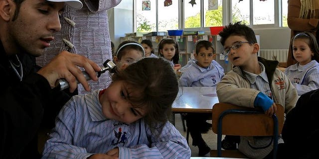 A volunteer checks a student before giving her a polio vaccine in the city of Nabatiyeh, Lebanon on October 31, 2006. Israel on Monday launches a mass campaign in the south of their country to vaccinate 200,000 children up to nine years old against polio, Health Minister Yael German said.