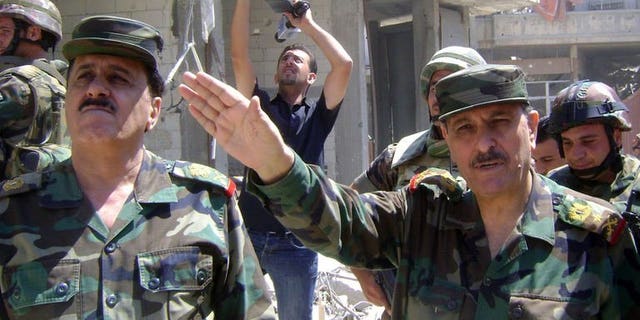 Picture released by the Syrian Arab News Agency (SANA) on August 5, 2013 shows Syrian general Fahd al-Freij (R), Defence minister and chief of the armed forces, talking to the media in the district of Khalidiyah in the central Syrian city of Homs. Freij visited army troops in Khaldiyeh, a district the army won back from rebel control in late July, state news agency SANA said on Monday.