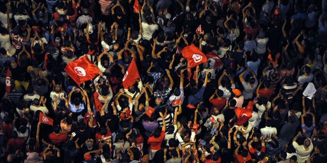 Tunisians wave flags and chant slogans in front of the Constituent Assembly headquarters against the Islamist government on August 4, 2013 in Tunis. Police used batons and tear gas against protesters who tried to break into local government offices in Sidi Bouzid, cradle of the 2011 revolution, an AFP journalist said.