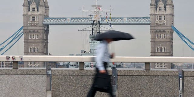 A city worker walks over London Bridge in central London. London shares closed lower on Monday as shares in HSBC tumbled after the global banking giant posted weaker-than-expected profits, traders said.