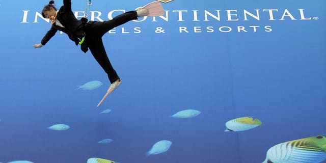 Performers dressed as divers hang off a wall during the opening ceremony for the InterContinental Hotels Group (IHG) hotel in Okinawa, Tokyo, on March 26, 2009. InterContinental Hotels Group on Tuesday announced a 25-percent increase in first-half net profits thanks to a strong showing by its American operations.