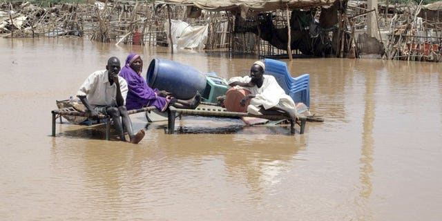Men sit with their belongings on a flooded Khartoum street last week. Heavy rains and flash floods in Khartoum and other parts of Sudan have killed 11 people and affected almost 100,000 in the past week, the United Nations said on Tuesday.