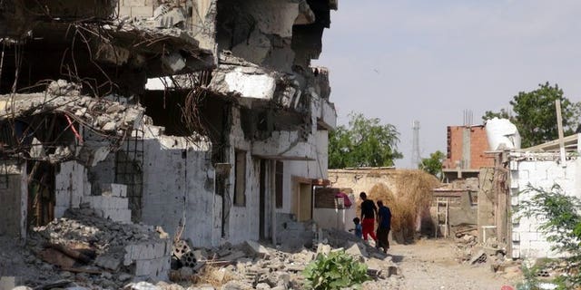 Yemenis walk past destroyed buildings in Zinjibar on December 5, 2012. Nasir al-Wuhayshi, a former aide to Al-Qaeda's late founder Osama bin Laden, tunnelled his way out of prison to become head of the Yemen-based Al-Qaeda in the Arabian Peninsula.