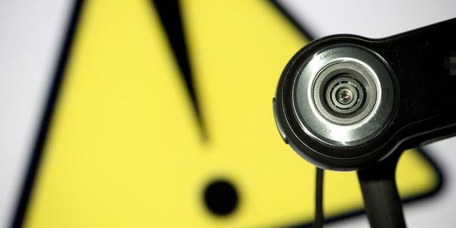 This file illustration photo shows a webcam positioned in front of a danger sign. Two Canadian men were charged Friday in the distribution of child pornography linked to the suicide of a girl who killed herself after months of cyber-bullying, following a sexual assault.
