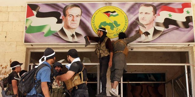 Rebel fighters tear down a poster of Syrian President Bashar al-Assad (R) and his late father and predecessor Hafez al-Assad (L) in the town of Deir Ezzor, on August 10, 2013. Nearly 60 Syrian soldiers and jihadists have been killed in three days of fighting in Deir Ezzor, the largest city in eastern Syria, where rebels have made advances, an NGO said Monday.