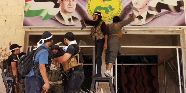 Rebel fighters tear down a poster of Syrian President Bashar al-Assad (R) and his late father and predecessor Hafez al-Assad (L) in the town of Deir Ezzor, on August 10, 2013. Nearly 60 Syrian soldiers and jihadists have been killed in three days of fighting in Deir Ezzor, the largest city in eastern Syria, where rebels have made advances, an NGO said Monday.