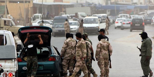 Libyan security force officers search a car at a checkpoint on May 16, 2013 in Benghazi. Some 14,000 prisoners who escaped from various Libyan detention centres after the 2011 uprising against Moamer Kadhafi are still on the run, the interior minister said.