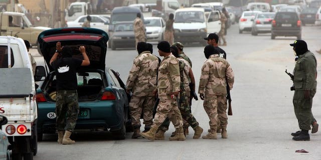 Libyan security force officers search a car at a checkpoint on May 16, 2013 in Benghazi. Some 14,000 prisoners who escaped from various Libyan detention centres after the 2011 uprising against Moamer Kadhafi are still on the run, the interior minister said.