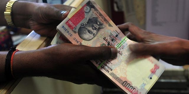 A customer receives a wad of Indian rupee notes from a foreign exchange dealer in Mumbai, on August 6, 2013. The rupee fell in early trade on Tuesday despite the government announcing new measures aimed at narrowing the current account deficit and aiding the ailing local currency.