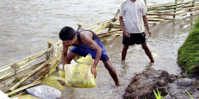This file photo shows local residents attempting to divert flood waters away from paddy fields near Kathmandu, on June 10, 2003. According to the latest government figures, more than 100 people have been killed in floods and landslides triggered by rains during the monsoon in 2013, which runs from June to September.
