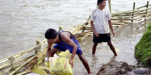 This file photo shows local residents attempting to divert flood waters away from paddy fields near Kathmandu, on June 10, 2003. According to the latest government figures, more than 100 people have been killed in floods and landslides triggered by rains during the monsoon in 2013, which runs from June to September.